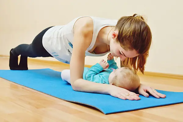 Mütter mit ihren Babys nehmen an einem Rückbildungskurs teil, um die Bauch-, Rücken- und Beckenbodenmuskulatur nach der Geburt zu kräftigen.
